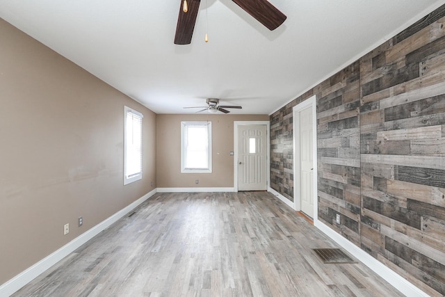 unfurnished room with light wood-type flooring, baseboards, an accent wall, visible vents, and a ceiling fan