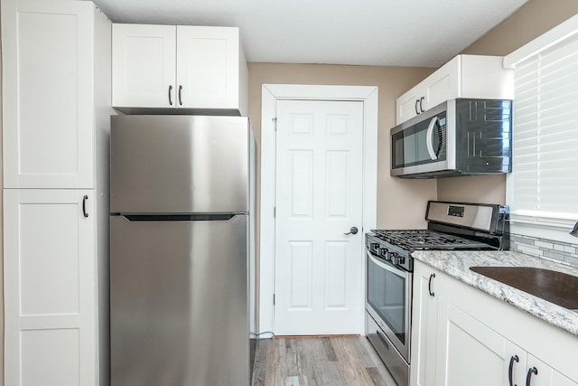 kitchen featuring light wood finished floors, white cabinets, and stainless steel appliances