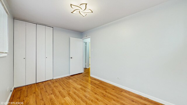 1317 Mackinaw Ave, Calumet City, IL 60409 - unfurnished bedroom with baseboards, light wood-style flooring, and a closet