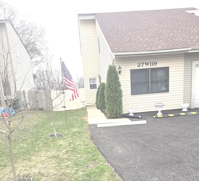 view of front facade featuring a front yard, roof with shingles, and a chimney