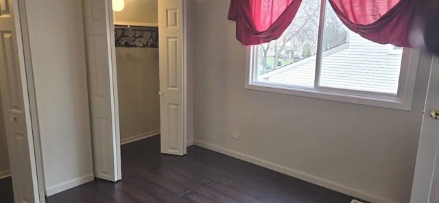 unfurnished bedroom with baseboards, dark wood-style flooring, and a closet