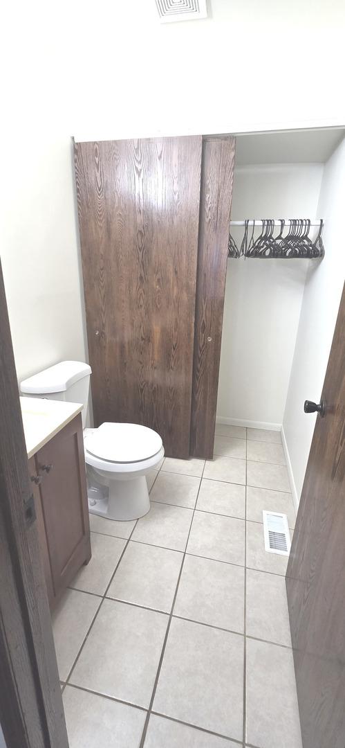 bathroom with tile patterned flooring, vanity, toilet, and visible vents