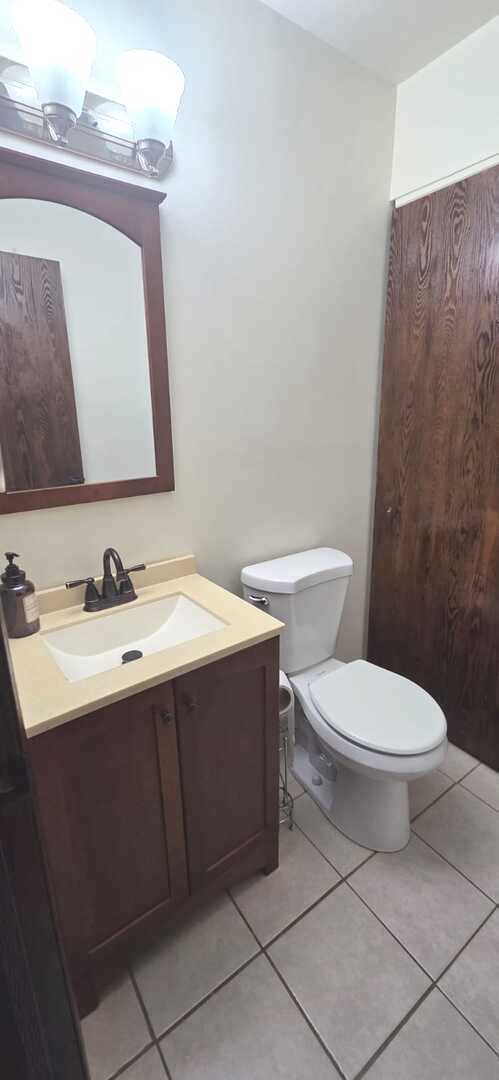 half bath with toilet, tile patterned flooring, and vanity