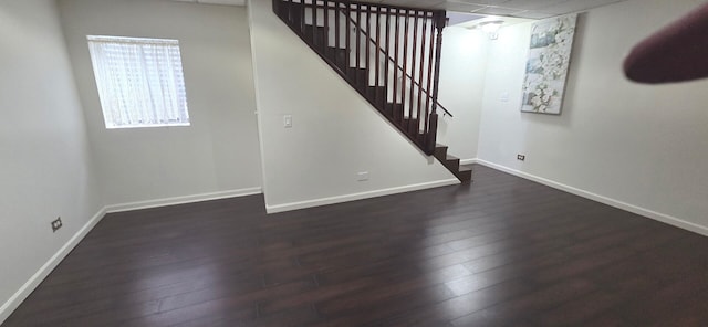 basement featuring baseboards, stairway, and dark wood-type flooring