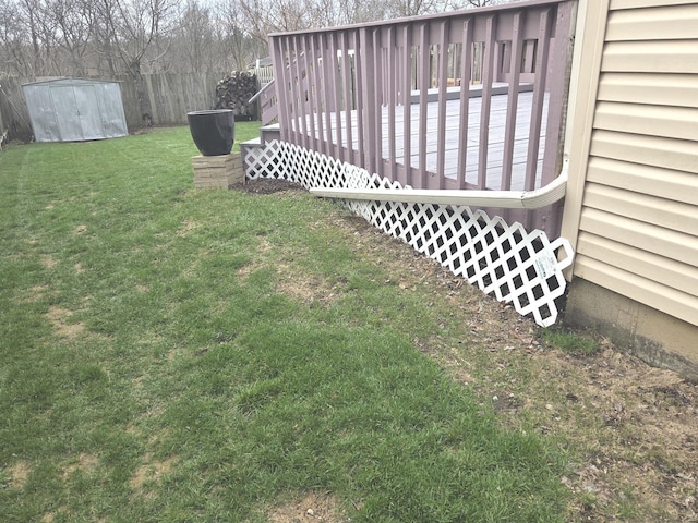 view of yard featuring fence, a wooden deck, and an outdoor structure