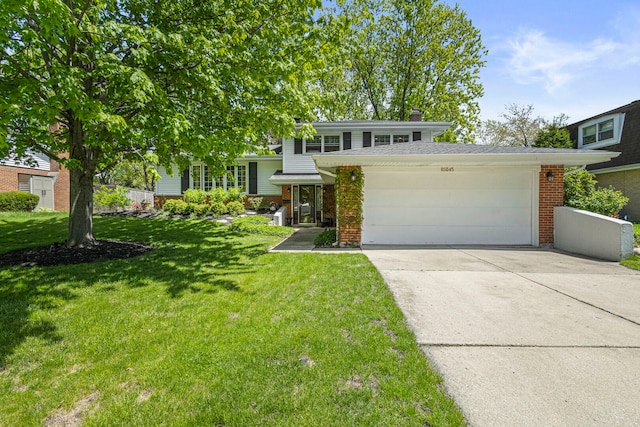 split level home featuring brick siding, an attached garage, driveway, a front yard, and a chimney