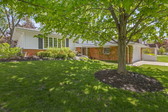 view of front of house with brick siding, concrete driveway, a front yard, and a garage