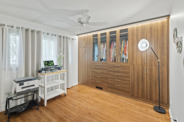 bedroom with light wood finished floors, an office area, and a ceiling fan