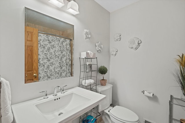 full bath with a sink, toilet, and curtained shower