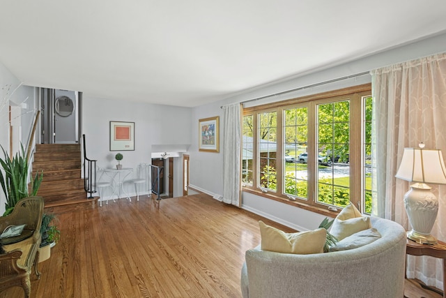 living room featuring wood finished floors, baseboards, and stairs