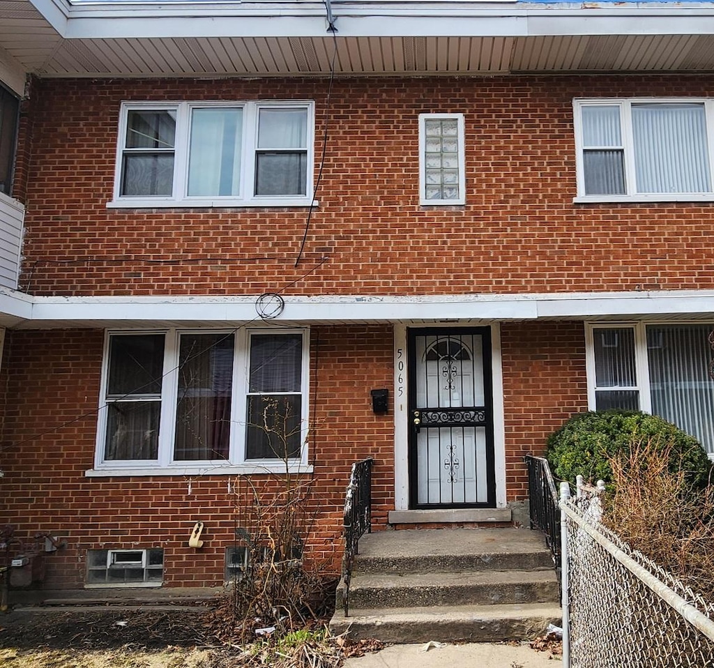 view of front of home featuring brick siding and fence