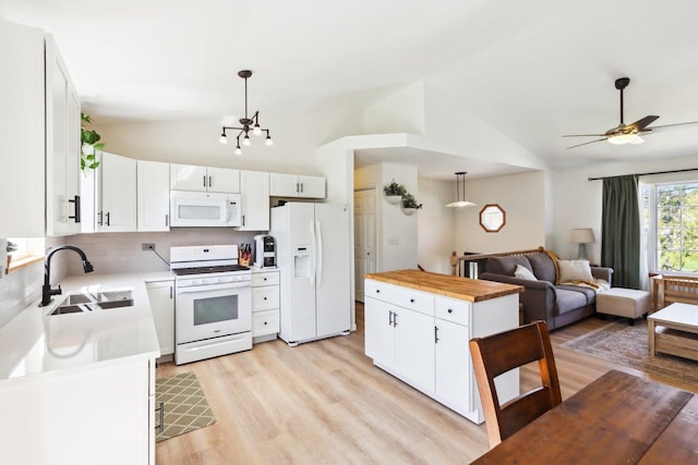 kitchen with a sink, light wood finished floors, vaulted ceiling, and white appliances