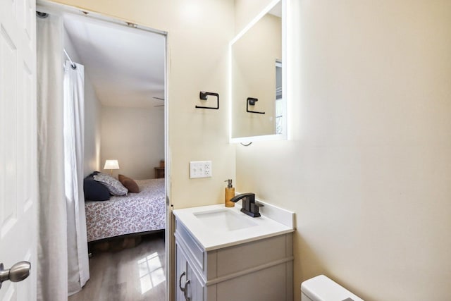 half bathroom featuring toilet, wood finished floors, and vanity