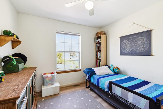 bedroom with baseboards, ceiling fan, wood finished floors, and visible vents