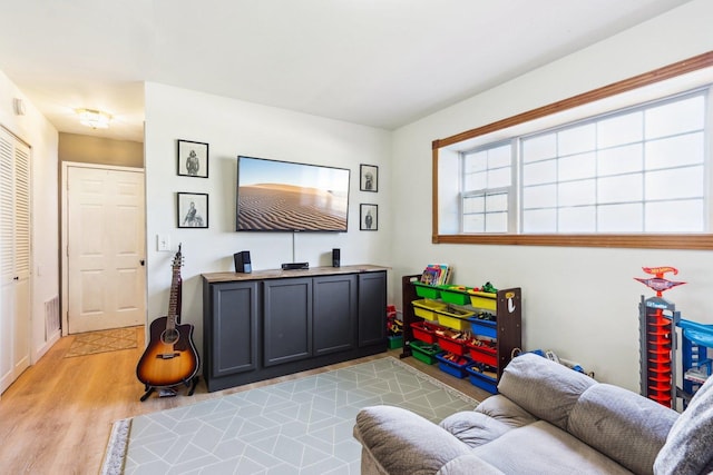 rec room featuring baseboards, light wood-type flooring, and visible vents