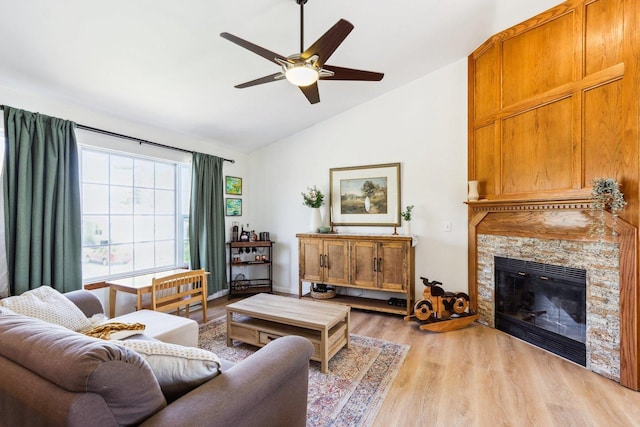 living room with light wood-style floors, ceiling fan, lofted ceiling, and a fireplace