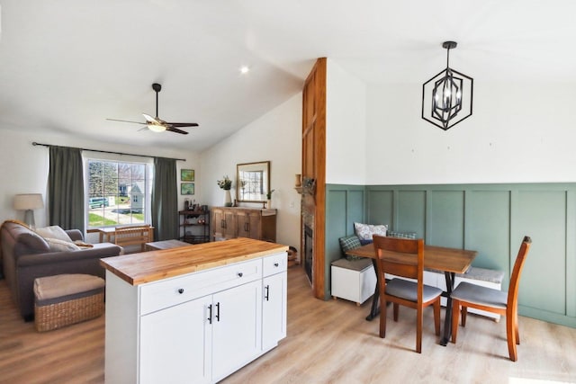 kitchen featuring white cabinets, butcher block countertops, ceiling fan with notable chandelier, and light wood-type flooring