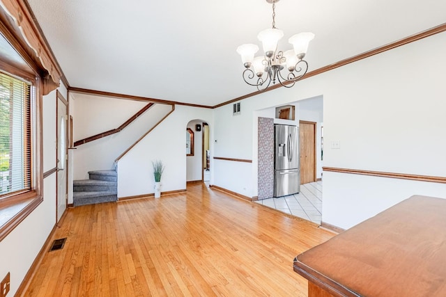 7733 Suburban Ln, Bridgeview, IL 60455 - unfurnished living room with a chandelier, arched walkways, light wood-style floors, crown molding, and stairway