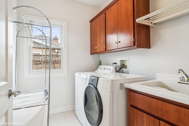 clothes washing area featuring light tile patterned floors, baseboards, washing machine and clothes dryer, a sink, and cabinet space