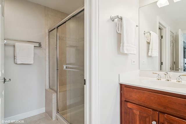 bathroom featuring vanity, baseboards, tile patterned floors, a skylight, and a stall shower