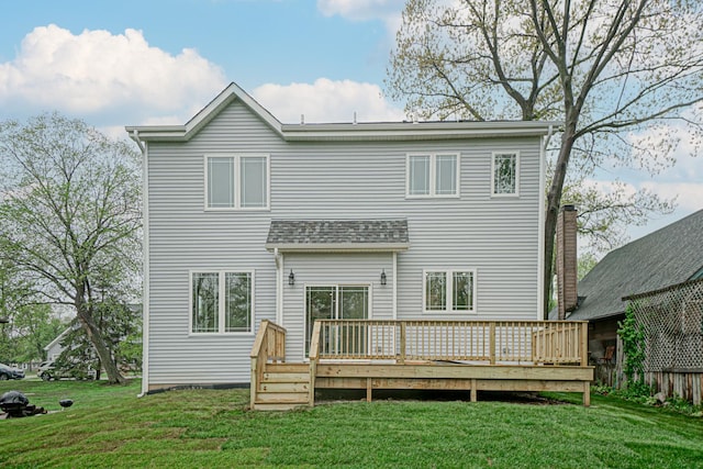 rear view of property featuring a wooden deck, fence, and a lawn
