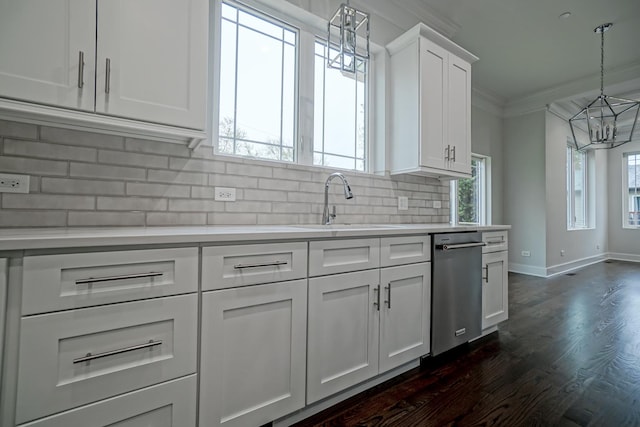 kitchen featuring crown molding, light countertops, a sink, decorative backsplash, and an inviting chandelier