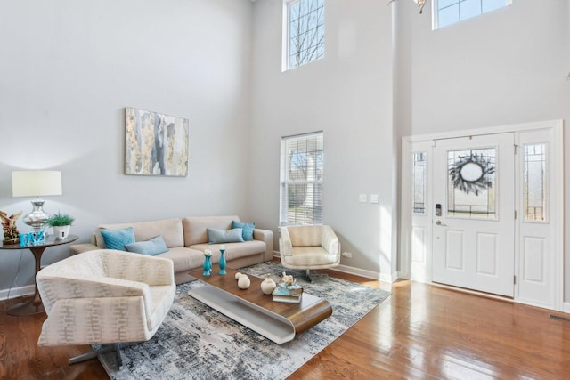 living room with a wealth of natural light, a high ceiling, baseboards, and wood finished floors