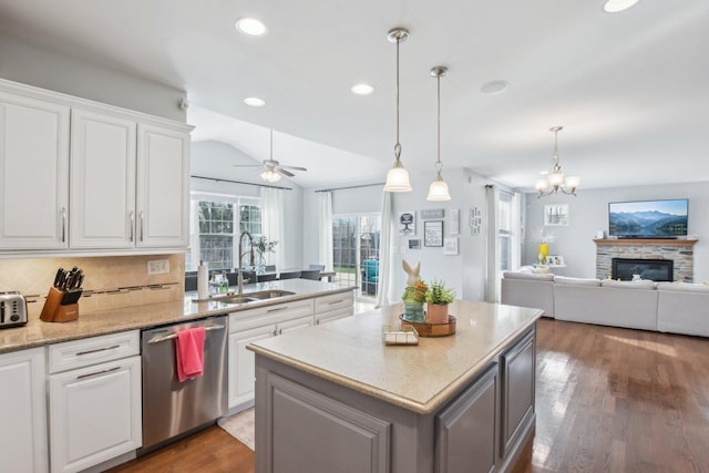 kitchen featuring white cabinets, a sink, light wood finished floors, stainless steel dishwasher, and decorative backsplash