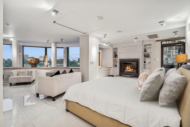 bedroom with marble finish floor, visible vents, attic access, and a glass covered fireplace