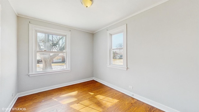spare room featuring baseboards, ornamental molding, and wood finished floors