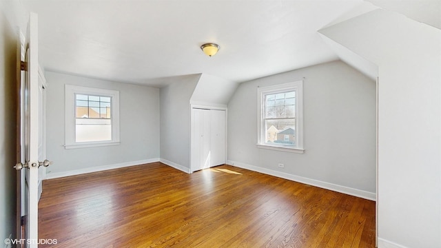bonus room with baseboards, vaulted ceiling, a wealth of natural light, and wood finished floors