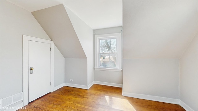 bonus room featuring baseboards, lofted ceiling, wood finished floors, and visible vents