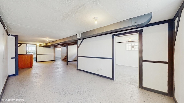 basement featuring a textured ceiling, baseboards, and visible vents