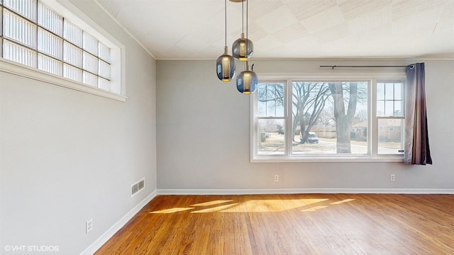 unfurnished dining area with crown molding, baseboards, wood finished floors, and visible vents