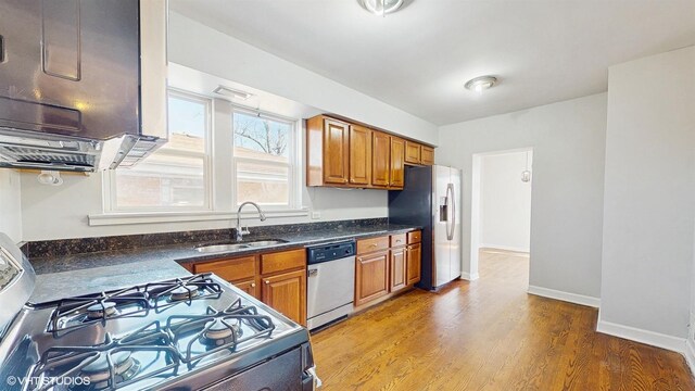 kitchen with brown cabinetry, stainless steel fridge, gas range oven, a sink, and dishwasher