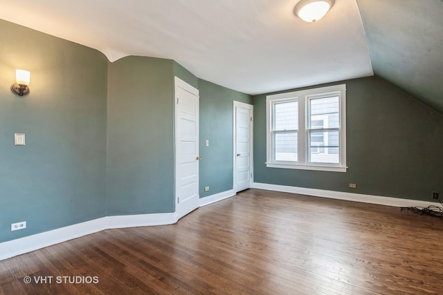 bonus room featuring lofted ceiling, baseboards, and dark wood-style floors