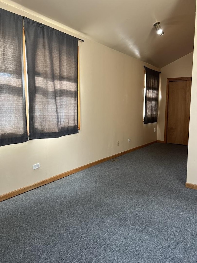 carpeted spare room with vaulted ceiling and baseboards