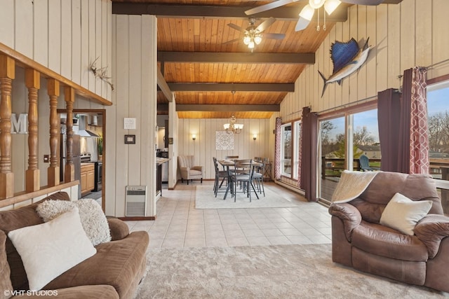 living area featuring ceiling fan with notable chandelier, light tile patterned floors, beamed ceiling, wood walls, and heating unit