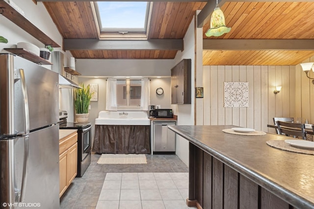 kitchen with light tile patterned flooring, a skylight, beamed ceiling, and appliances with stainless steel finishes