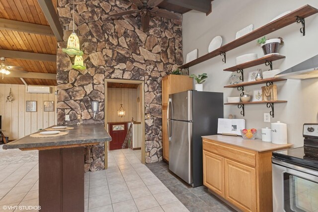 kitchen featuring a peninsula, ceiling fan, beamed ceiling, and stainless steel appliances