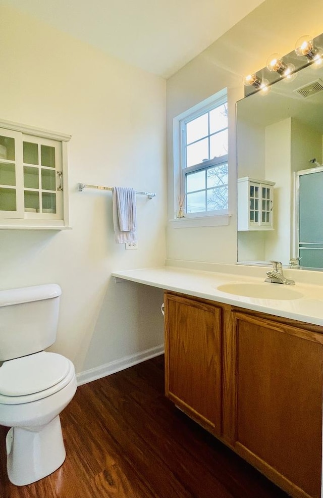 bathroom with wood finished floors, visible vents, toilet, vanity, and baseboards
