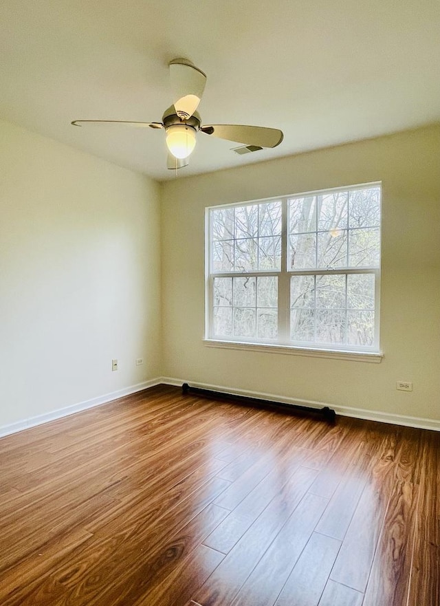 empty room with a ceiling fan, visible vents, dark wood-style floors, and a healthy amount of sunlight