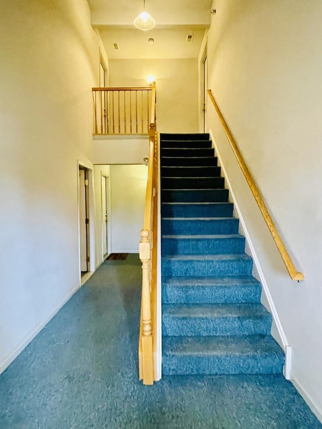 staircase with carpet, a high ceiling, and baseboards