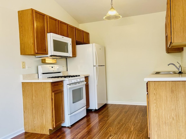 kitchen featuring dark wood-style flooring, a sink, white appliances, and light countertops
