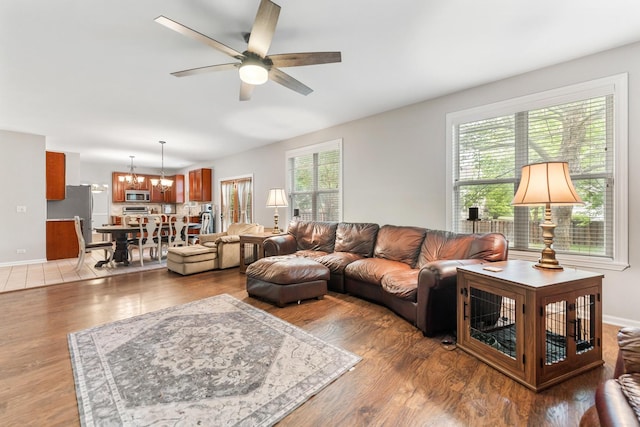 2571 Rourke Dr, Aurora, IL 60503 - living room featuring a chandelier, a ceiling fan, light wood-style floors, and baseboards