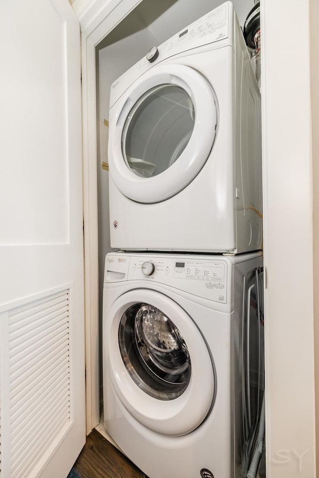 clothes washing area with stacked washer and dryer, laundry area, and dark wood finished floors