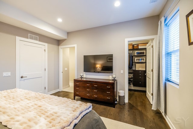 bedroom with dark wood-style flooring, a closet, recessed lighting, a walk in closet, and visible vents