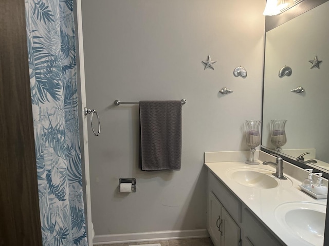 full bathroom with curtained shower, double vanity, a sink, and baseboards