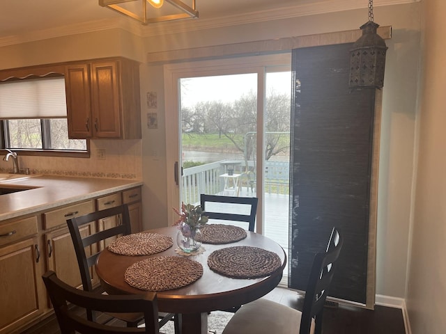dining room featuring crown molding and a water view