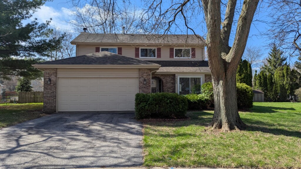 1323 Middlebury Dr, Aurora, IL 60504 - traditional-style house featuring fence, aphalt driveway, a front yard, brick siding, and a garage